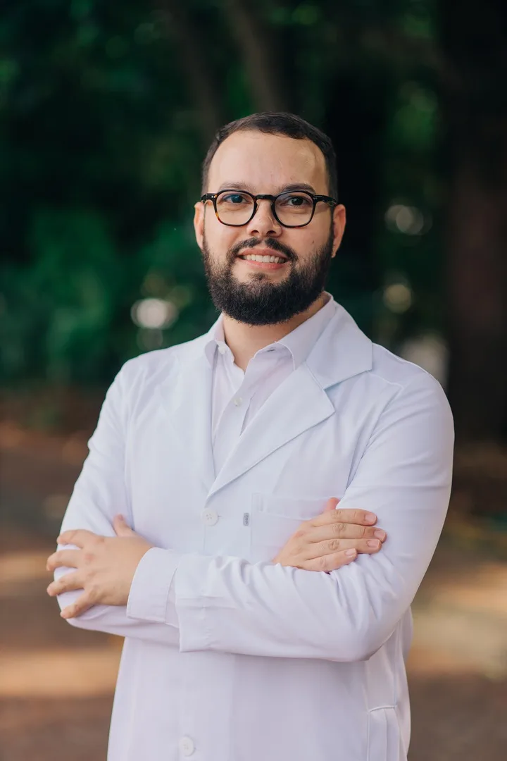 Dr. Fillipe Lopes de jaleco branco, sorrindo, com os braços cruzados